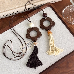 Vintage bohemian necklace with wood flower pendant and tassels on linen background