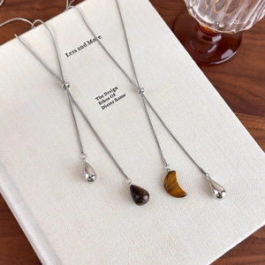 Detail of adjustable silver snake chain necklace with tiger eye and crescent stone pendants
