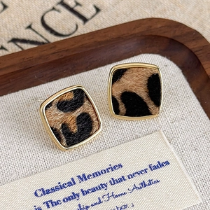 Gros plan de boucles d'oreilles carrées léopard avec bordure dorée sur fond vintage rétro