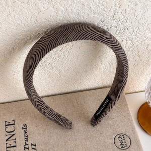 Close-up of handmade brown sponge headband featuring a vintage knit texture and tag