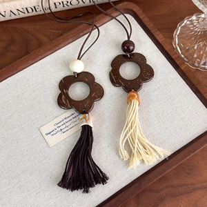 Detail of bohemian hollow wooden flower pendants with cotton fringe tassels on a tray