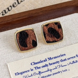Détail de boucles d'oreilles carrées léopard vintage avec cadre doré et texture en velours