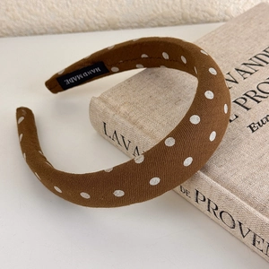 Close-up of brown polka dot headband with handmade label on vintage fabric book background