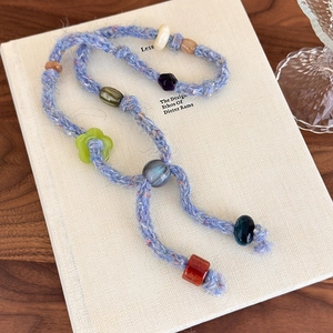 Close-up of handmade boho knit necklace with colorful beads and floral charms