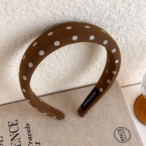 Detailed macro view of the handmade brown polka dot headband on a linen display stand