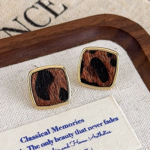 Détails de boucles d'oreilles carrées imprimé léopard avec cadre doré sur fond de tissu