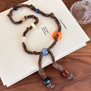 Detail of bohemian knitted bead necklace with brown wool rope on a decorative book