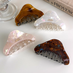 Detailed close-up of acetate claw clips with retro patterns and gold Barrette lettering