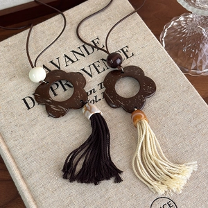 Detailed macro of vintage coconut shell flower pendant with long hanging tassels