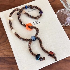Close-up of vintage hand-knitted cord necklace with colorful beads on a book
