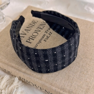 Detail view of plaid wool headband with silver studs on a vintage book background