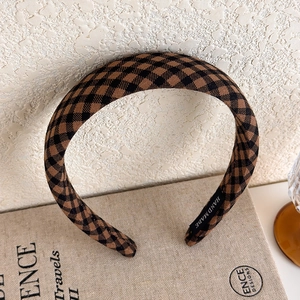 Detail of a brown checkered padded headband with a handmade label on a vintage book