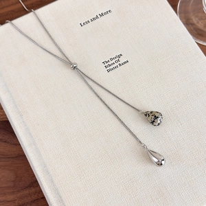 Detail of silver Y-shaped sweater necklace featuring dalmatian stone and metallic teardrops
