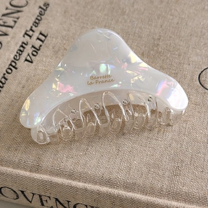 Macro shot of colorful pearlescent acetate hair claw clip with golden branding text