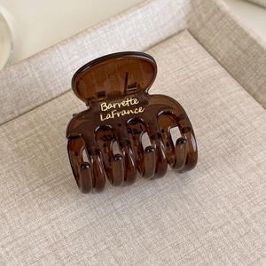 Dettaglio molletta per capelli ambra con scritta Barrette LaFrance dorata su acrilico