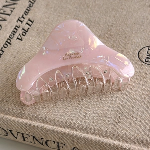 Detail of pink marble acetate hair claw clip with rhinestones on linen background
