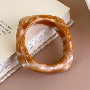 Vista dettagliata del bracciale in acrilico con motivo marmo ambra e design geometrico