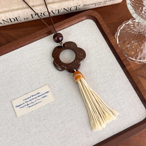Macro detail of retro hollow wood flower pendant and cotton tassel on vintage books