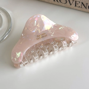 Detail of peach pink pearlescent hair claw with marble pattern and rhinestone accents