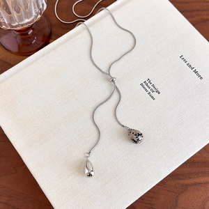Detail of silver Y-shaped tassel necklace with tiger eye stone and metallic teardrop pendants