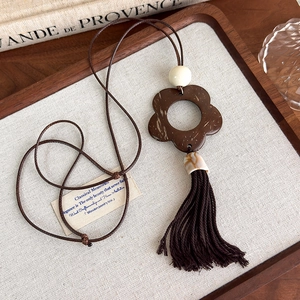 Close-up of vintage hollow flower pendant with brown tassels and carved cloud patterns