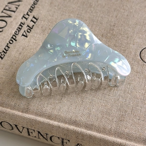 Detail of blue acetate shark hair claw with gold engraving on vintage book background