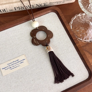 Macro shot of retro wooden flower pendant with silk tassels on a long sweater necklace