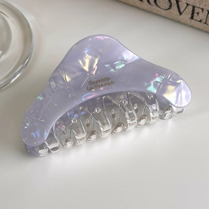 Close-up of lavender acetate hair claw with iridescent texture and gold lettering detail