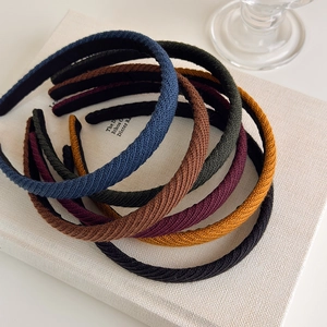 Set di sei cerchietti in maglia a costine colorata in blu, verde e bordeaux su libri