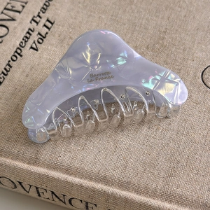Close-up of lavender acetate hair claw clip with pearlescent texture and gold spring