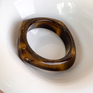 Dettaglio del bracciale in acrilico con motivo marmorizzato quadrato su ciotola bianca
