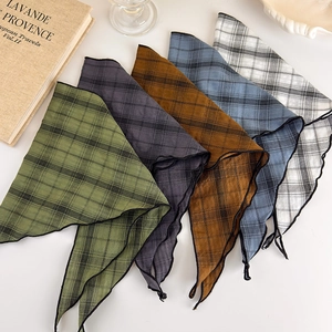 Detail view of retro plaid triangle scarves in green, blue, and brown tones on a beige background