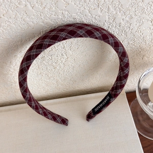 Detailed shot of a red plaid headband on a book featuring a handmade label and soft texture