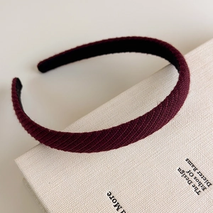 Dettaglio ravvicinato di un cerchietto in tessuto twill bordeaux su un libro bianco