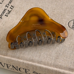 Detailed close-up of amber tortoiseshell acetate hair claw on a vintage book