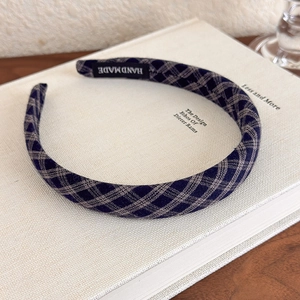 Detailed texture of navy and grey plaid headband with a handmade woven label on book