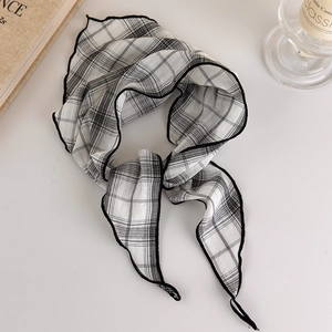 Detailed close-up of retro black and white checkered thin scarf with wavy edge stitching