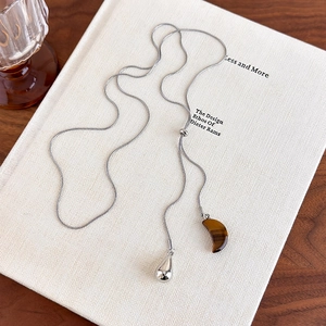 Detailed macro of tiger eye stone moon pendant and silver water drop on adjustable chain