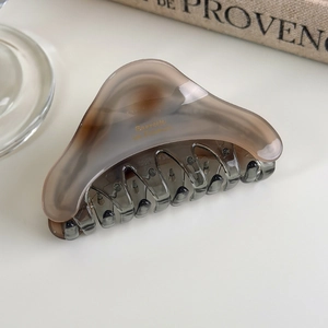 Detail of a smoky grey acetate claw clip with gold French Barrette engraving on a table