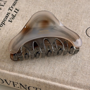 Detailed macro view of the marble texture and gold lettering on the acetate hair claw