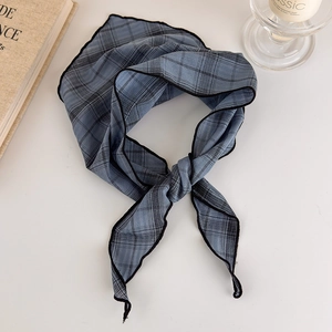 Detail of blue plaid silk scarf with black check pattern and rolled edges in bow shape