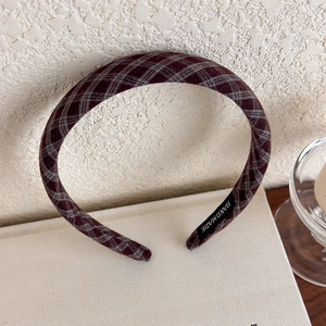 Detail view of burgundy plaid headband with handmade woven label on inner fabric