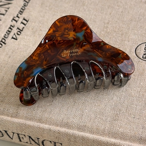 Macro view of vintage acetate hair claw with amber tortoise shell pattern and gold lettering