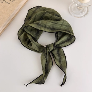Detail of dark green plaid silk scarf with black hemmed edges tied in a decorative knot