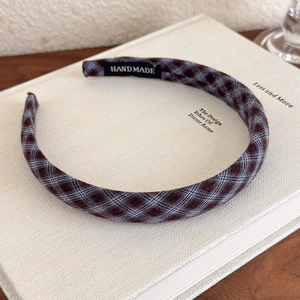 Detail of a thin plaid headband with a handmade label on a vintage book