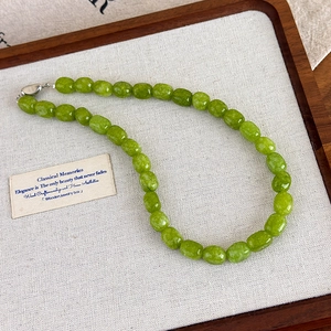 Detail of green natural stone beaded necklace with silver clasp on a wooden tray