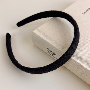 Dettaglio macro della trama in maglia nera e strisce diagonali sulla fascia per capelli