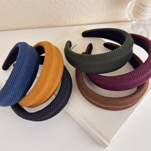 Set of six knitted textured headbands in autumn colors displayed on a white book