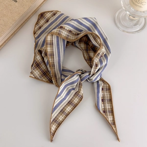 Detailed view of vintage plaid silk scarf styled with a knot on a minimalist background