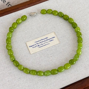 Close-up of green natural stone beaded necklace with faceted texture and silver metal clasp